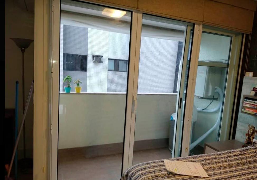 Porta acústica de correr instalada em quarto, com vista para o prédio vizinho