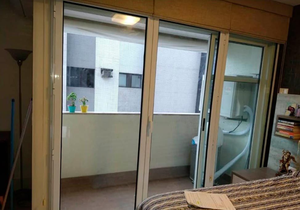 Portas de correr acústicas instaladas em quarto, com vista para o prédio vizinho